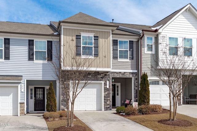 townhome / multi-family property featuring board and batten siding, stone siding, concrete driveway, and a garage