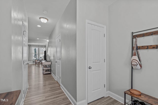 hall with light wood-type flooring and baseboards