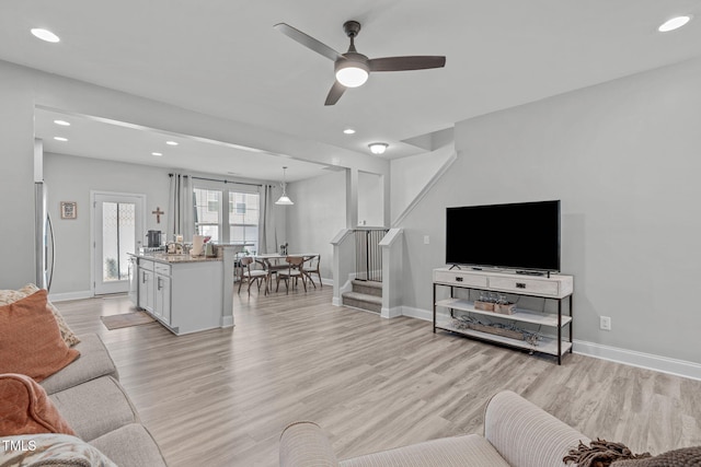 living room with light wood finished floors, stairs, and baseboards