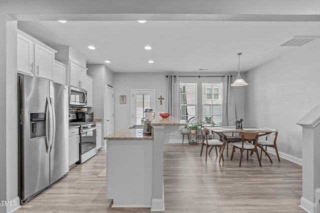 kitchen featuring stainless steel appliances, visible vents, white cabinets, light stone countertops, and light wood-type flooring