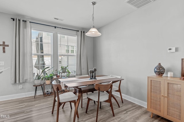 dining space with light wood-style flooring, visible vents, and baseboards