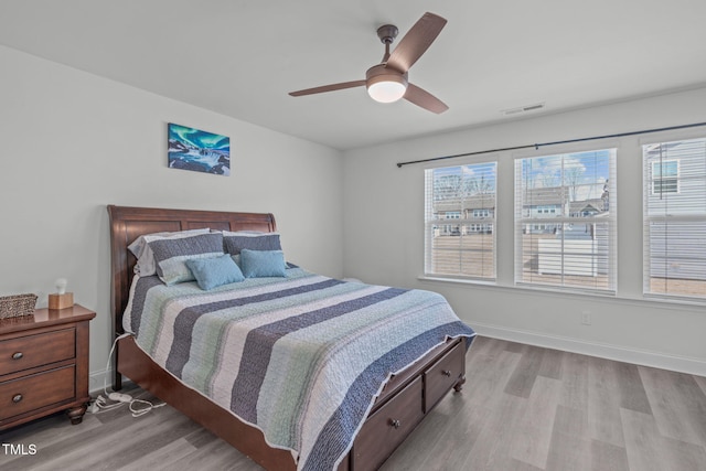 bedroom with a ceiling fan, wood finished floors, visible vents, and baseboards