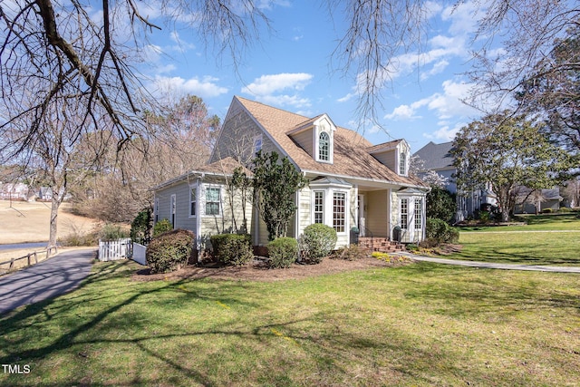 cape cod home with a shingled roof and a front lawn