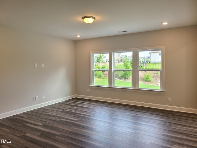 unfurnished room featuring recessed lighting, dark wood-style flooring, visible vents, and baseboards