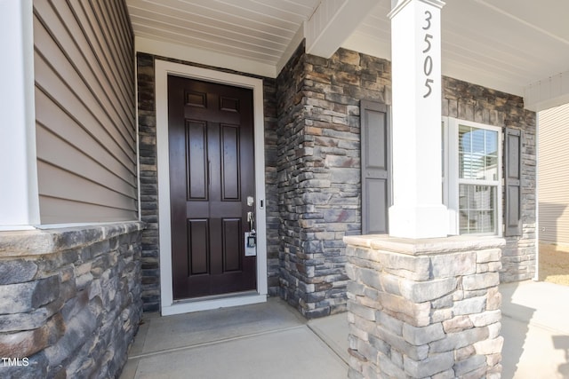 doorway to property with stone siding and covered porch