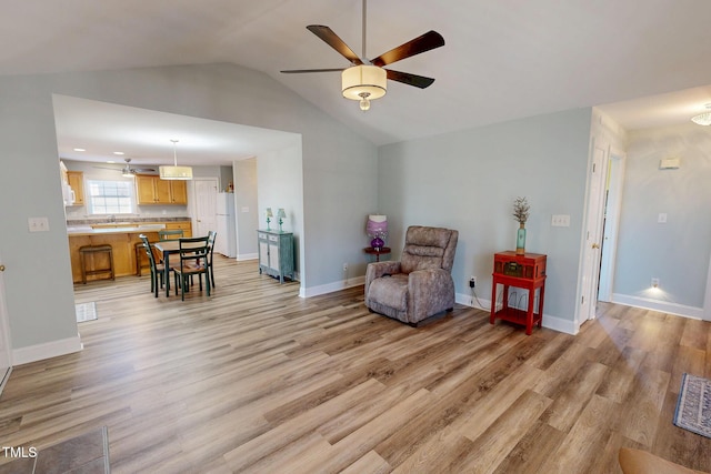 sitting room featuring vaulted ceiling, ceiling fan, light wood finished floors, and baseboards