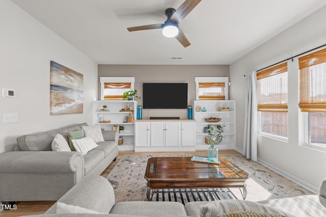 living area featuring ceiling fan, visible vents, and baseboards