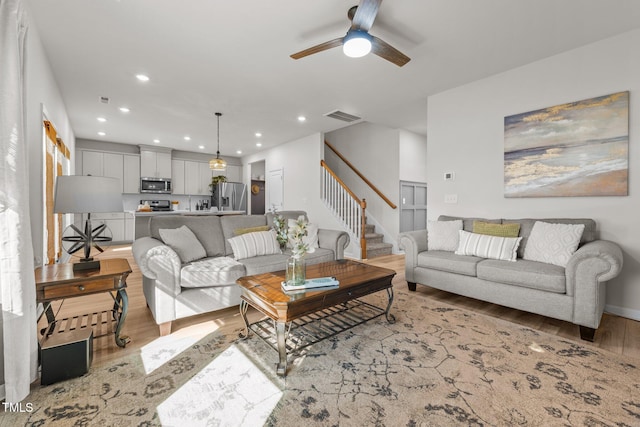 living room with recessed lighting, visible vents, light wood-style flooring, a ceiling fan, and stairs