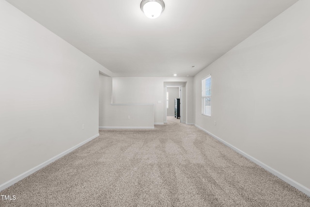 spare room with light carpet and baseboards