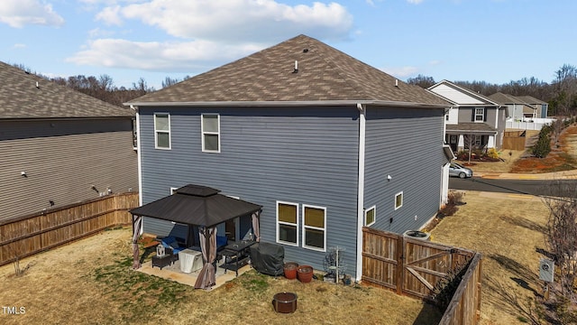 rear view of house with a gazebo, roof with shingles, a patio area, and a fenced backyard