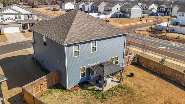 back of property featuring a shingled roof, a fenced backyard, and a residential view