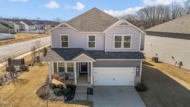 view of front facade featuring central AC unit, an attached garage, covered porch, driveway, and board and batten siding