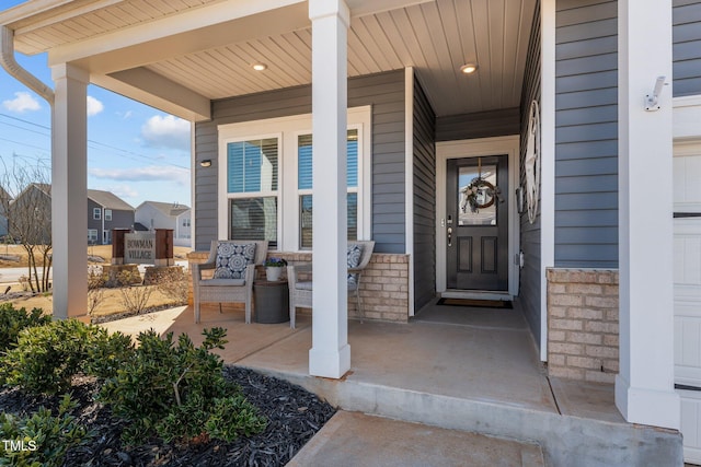 view of exterior entry with a garage, stone siding, and a porch