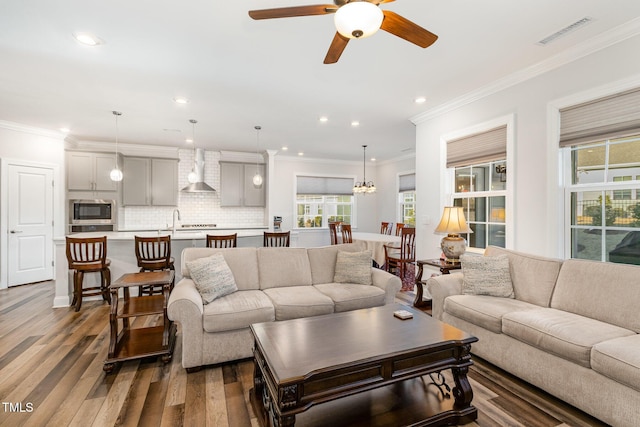 living area with dark wood-style floors, ornamental molding, visible vents, and recessed lighting