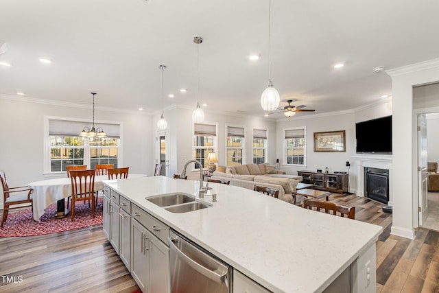 kitchen with a center island with sink, hanging light fixtures, stainless steel dishwasher, open floor plan, and a sink