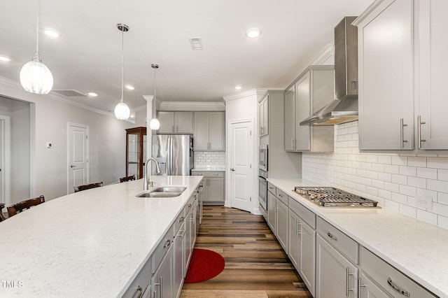 kitchen featuring wall chimney exhaust hood, stainless steel appliances, a sink, and decorative light fixtures