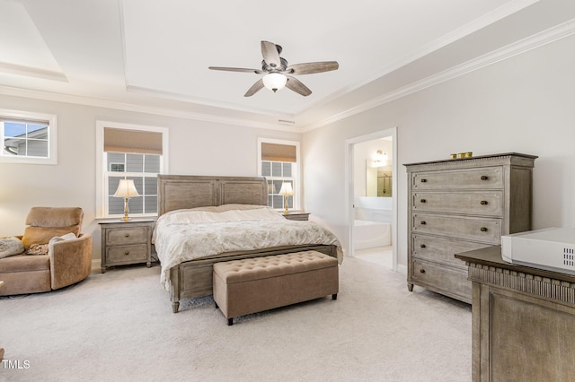 bedroom with light carpet, a tray ceiling, ornamental molding, and connected bathroom