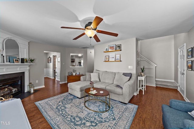 living room featuring a ceiling fan, wood finished floors, baseboards, and a fireplace with flush hearth
