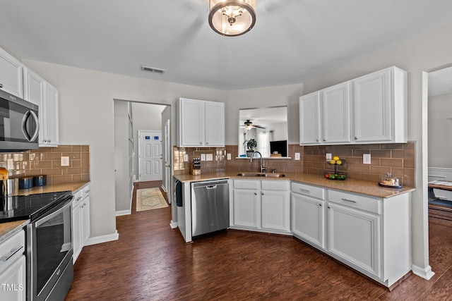 kitchen featuring stainless steel appliances, a sink, backsplash, white cabinets, and dark wood-style floors