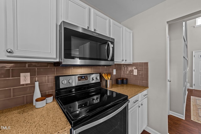 kitchen featuring stainless steel microwave, electric stove, white cabinets, and backsplash