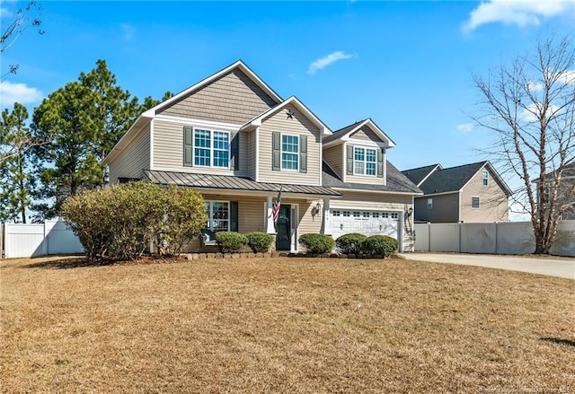 view of front facade with a standing seam roof, fence, a front lawn, and concrete driveway