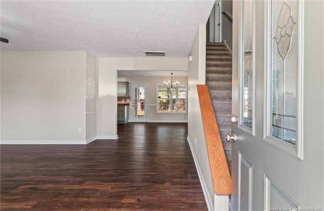 foyer featuring baseboards, visible vents, dark wood finished floors, stairway, and a chandelier