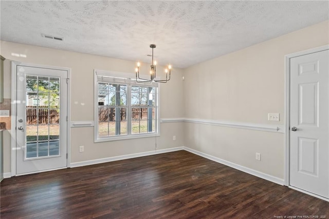 unfurnished dining area featuring a notable chandelier, visible vents, dark wood finished floors, and a textured ceiling