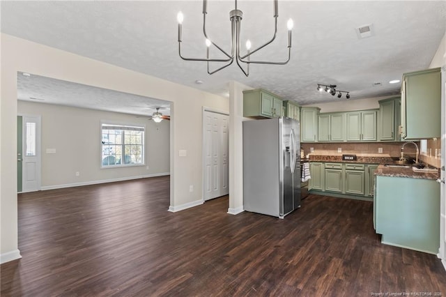 kitchen featuring dark countertops, stainless steel refrigerator with ice dispenser, green cabinetry, and open floor plan