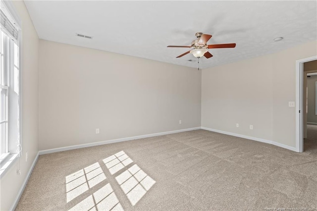 unfurnished room featuring baseboards, visible vents, ceiling fan, and light colored carpet