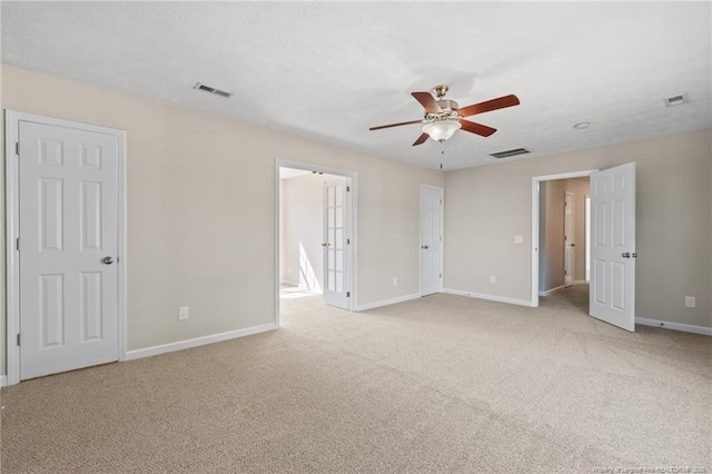 unfurnished room featuring light carpet, a ceiling fan, visible vents, and baseboards