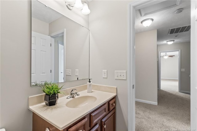 bathroom featuring visible vents, ceiling fan, vanity, a textured ceiling, and baseboards