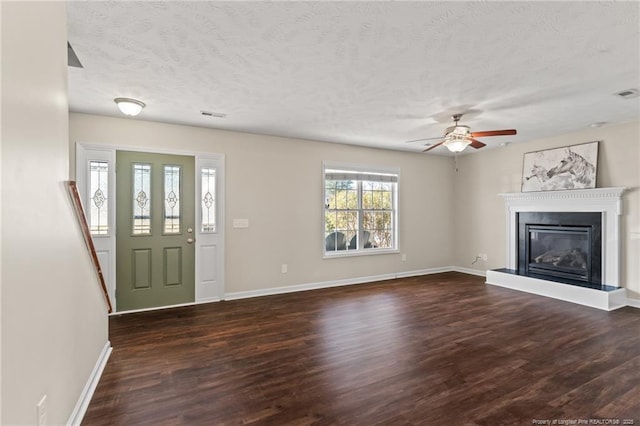 unfurnished living room featuring a textured ceiling, dark wood-style flooring, visible vents, and baseboards