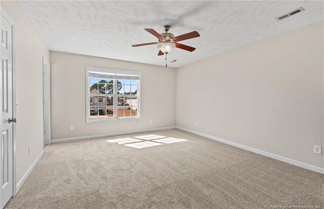 unfurnished room featuring baseboards, visible vents, light carpet, and ceiling fan
