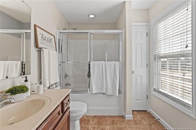 full bathroom featuring toilet, combined bath / shower with glass door, a healthy amount of sunlight, and vanity