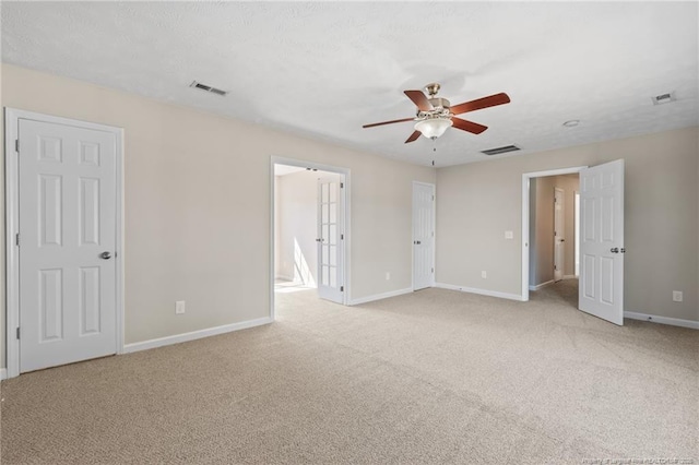 unfurnished bedroom with baseboards, visible vents, ceiling fan, and light colored carpet