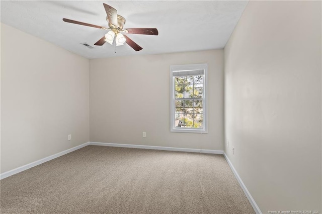 carpeted empty room with a ceiling fan, visible vents, and baseboards