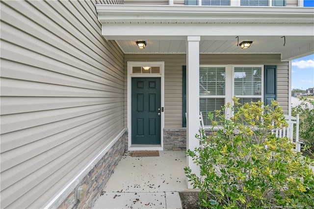 property entrance with covered porch and stone siding