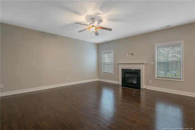 unfurnished living room with a glass covered fireplace, a healthy amount of sunlight, visible vents, and baseboards