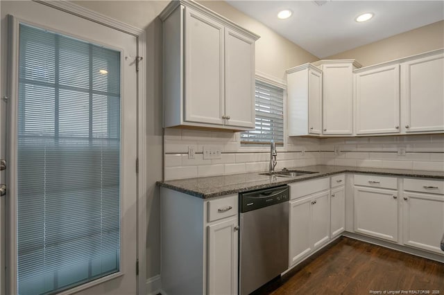 kitchen featuring tasteful backsplash, stainless steel dishwasher, white cabinets, a sink, and dark stone counters