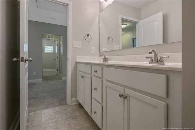 bathroom featuring tile patterned floors, a sink, baseboards, and double vanity