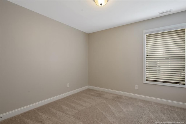 unfurnished room featuring light colored carpet, visible vents, and baseboards