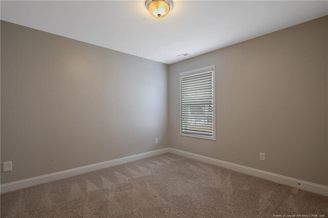 empty room with carpet floors, visible vents, and baseboards