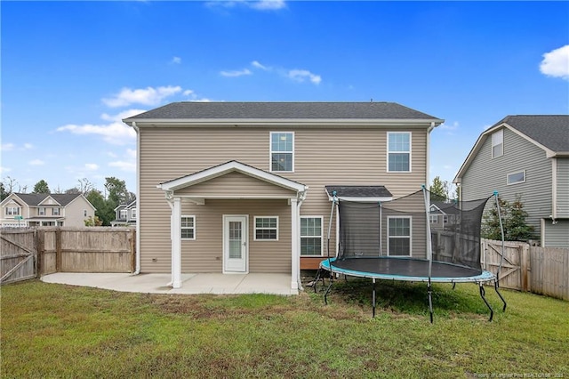 rear view of house with a patio, a trampoline, a fenced backyard, and a lawn