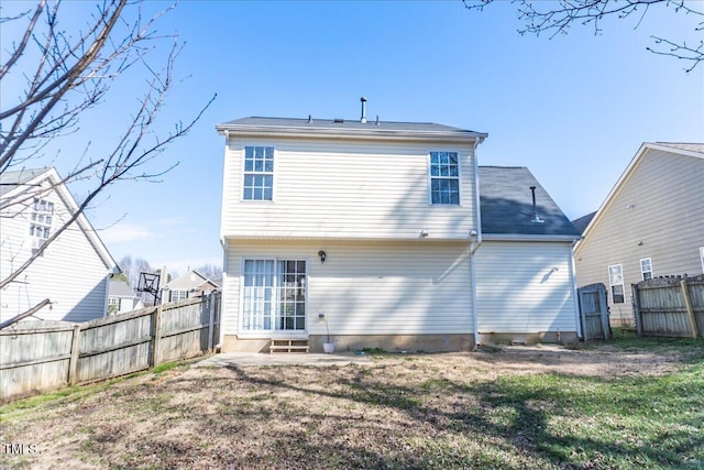 rear view of property with entry steps, a yard, and fence