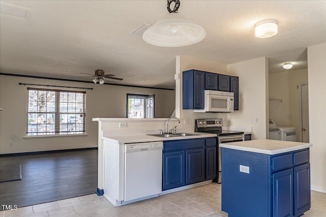 kitchen featuring white appliances, washing machine and dryer, blue cabinetry, and a sink