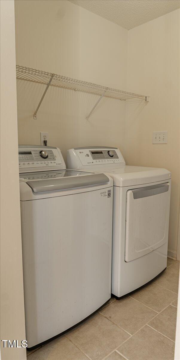 laundry room with light tile patterned floors, laundry area, separate washer and dryer, and a textured ceiling