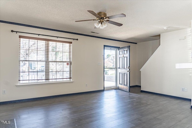 empty room featuring a healthy amount of sunlight, visible vents, and wood finished floors