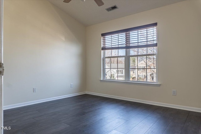 empty room with baseboards, ceiling fan, visible vents, and dark wood-style flooring