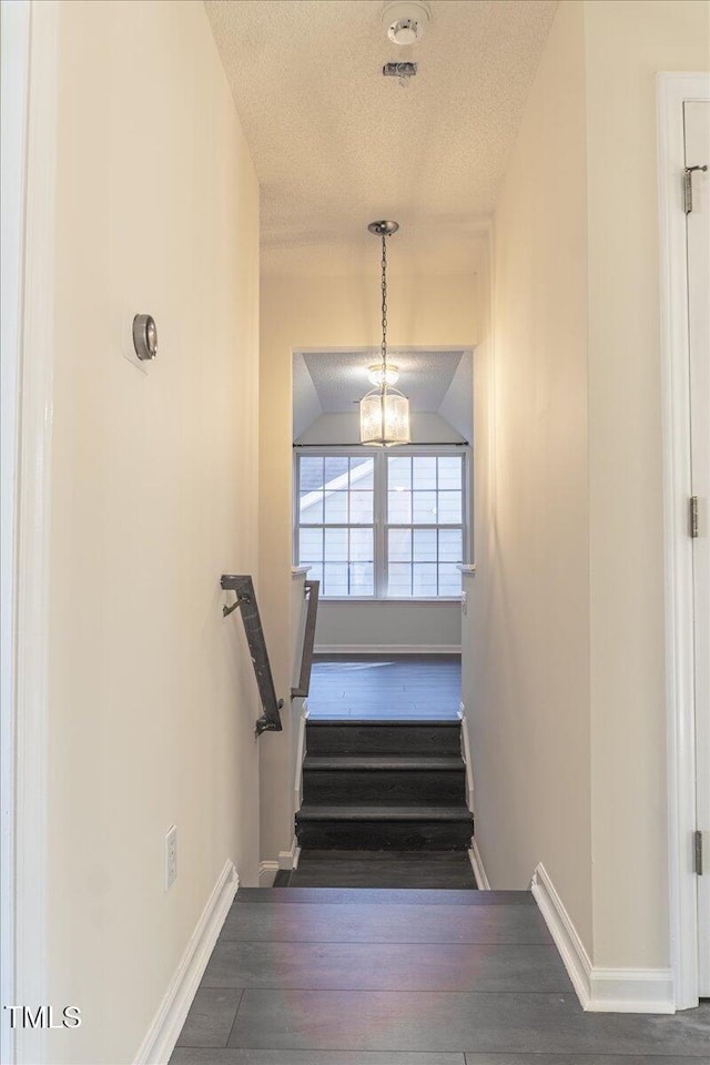 staircase with lofted ceiling, baseboards, a textured ceiling, and hardwood / wood-style floors