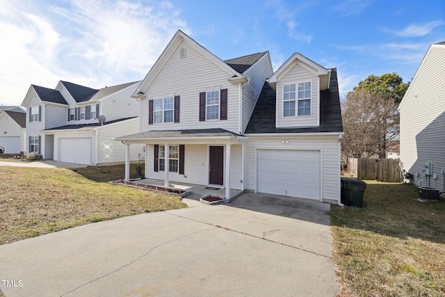 traditional home with a garage, concrete driveway, a front lawn, and fence